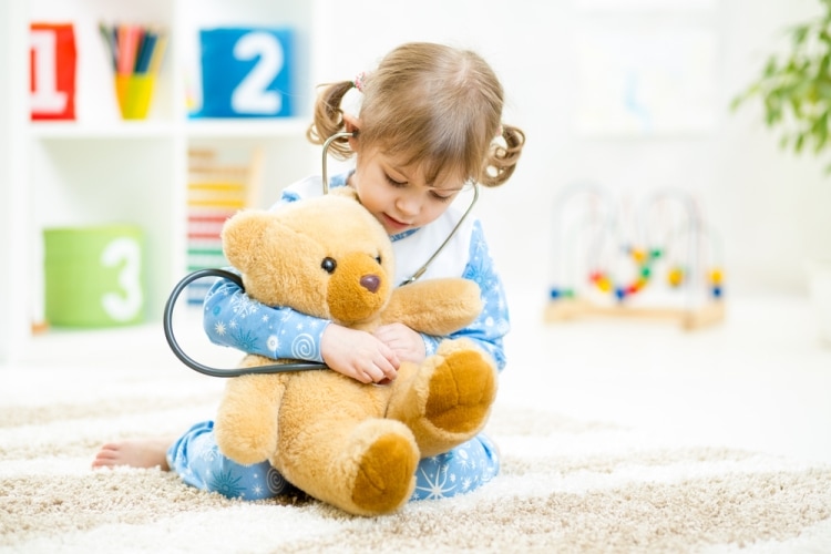 Знакомство детей с профессиями - маленькая девочка играет в доктора с плюшевым медвежонком