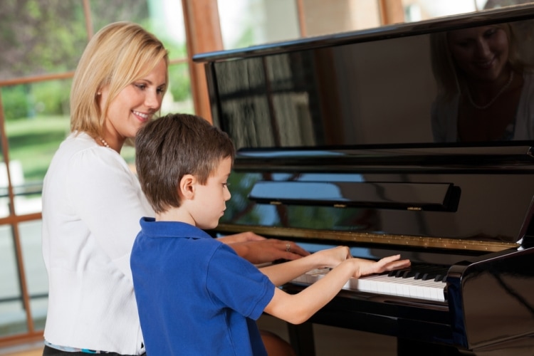 Как научить ребенка играть на фортепиано - мальчик с преподавателем играет на фортепиано