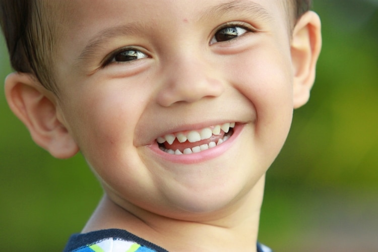 Как ухаживать за молочными зубами - мальчик с белыми зубками широко улыбается