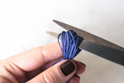 Кукла из мулине - ножницами синие нитки разрезаются по краям