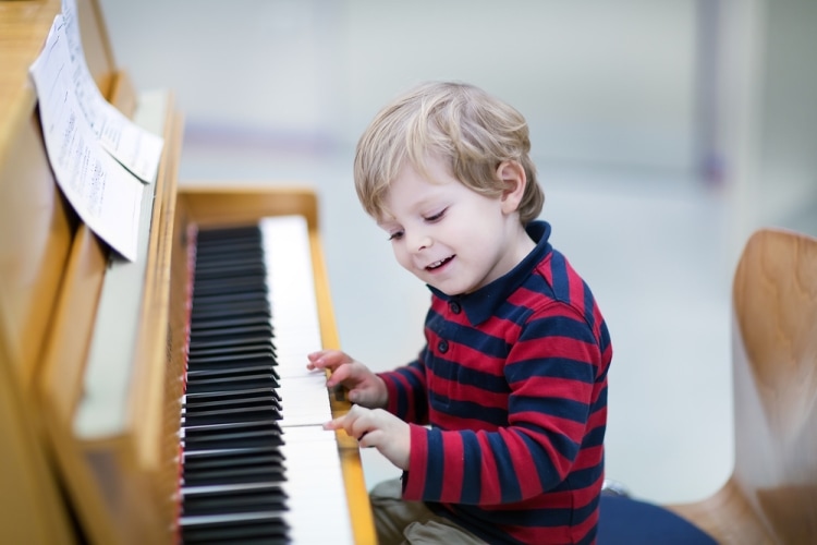 Как научить ребенка играть на фортепиано - мальчик увлеченно играет на фортепиано