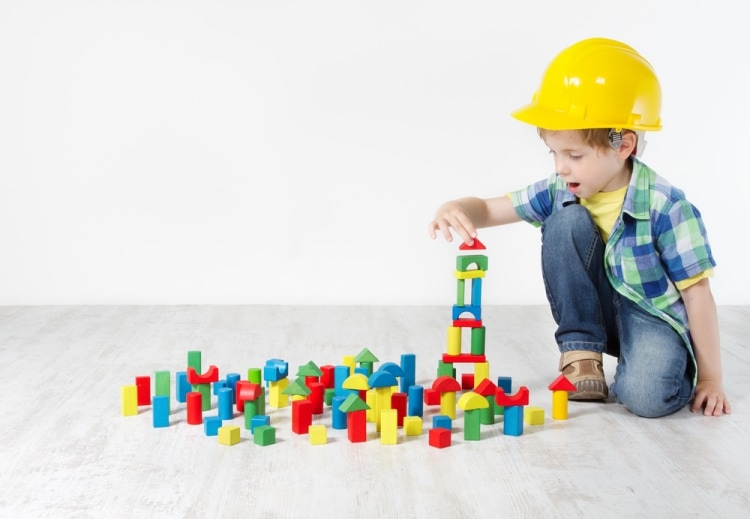 Эмоциональное развитие детей - мальчик в каске строителя собирает башню из конструктора