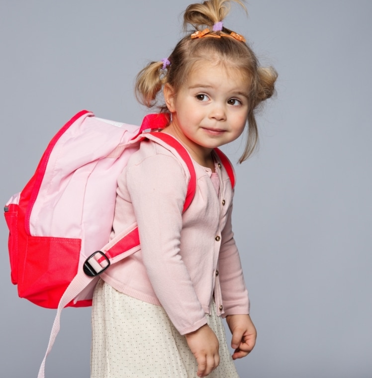 Выбираем портфель для первоклассника - девочка с тяжелым большим рюкзаком за плечами
