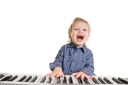Выбираем гитару для ребенка - довольный маленький мальчик играет на пианино