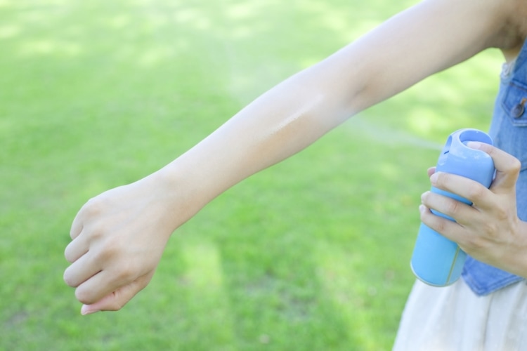 Защита детей от насекомых - девочка брызгает на руку спрей от насекомых